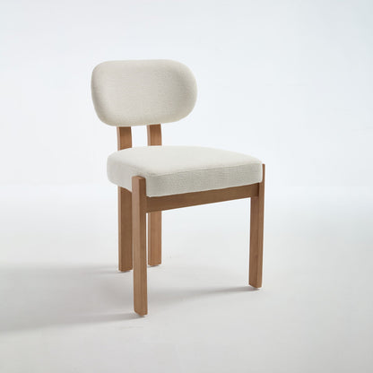 Two light blue upholstered dining chairs with ergonomic backrests and wood legs at a dining table