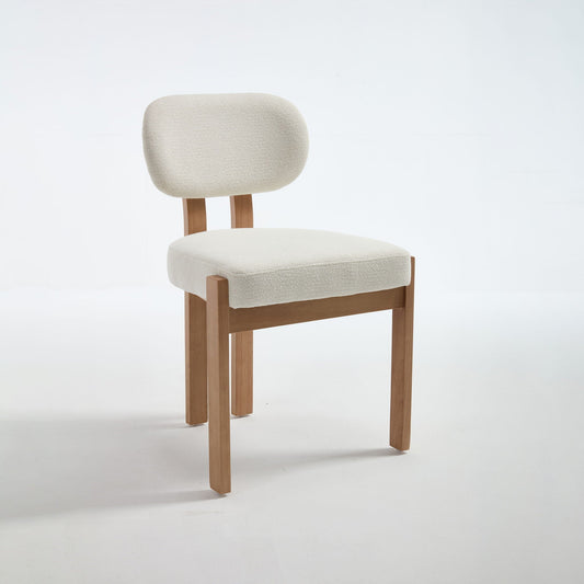 Two light blue upholstered dining chairs with ergonomic backrests and wood legs at a dining table