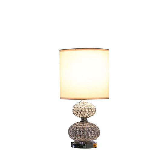 Silver chrome filigree cage table lamp with acrylic beads and white drum shade on a nightstand
