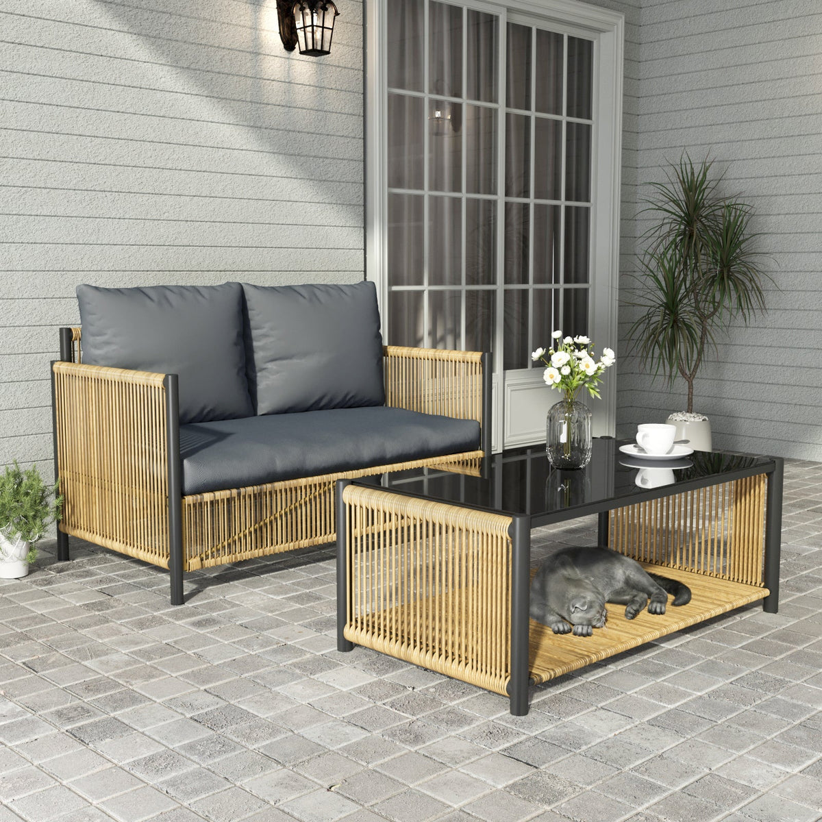 Black and brown PE wicker 2-seater outdoor sofa with grey cushions and glass coffee table on a patio