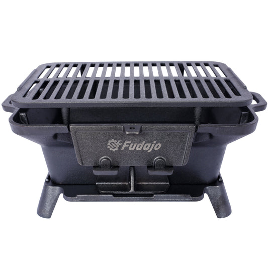 Black enameled oval cast iron tabletop charcoal grill with removable grates on a patio table