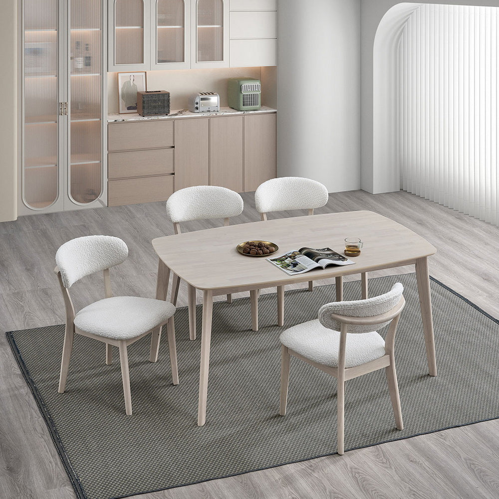 White-washed Scandinavian dining table with curved upholstered chairs in a bright breakfast area