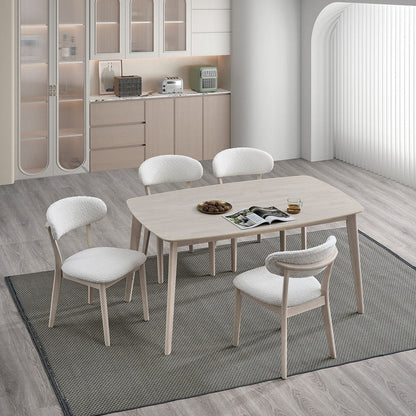 White-washed Scandinavian dining table with curved upholstered chairs in a bright breakfast area