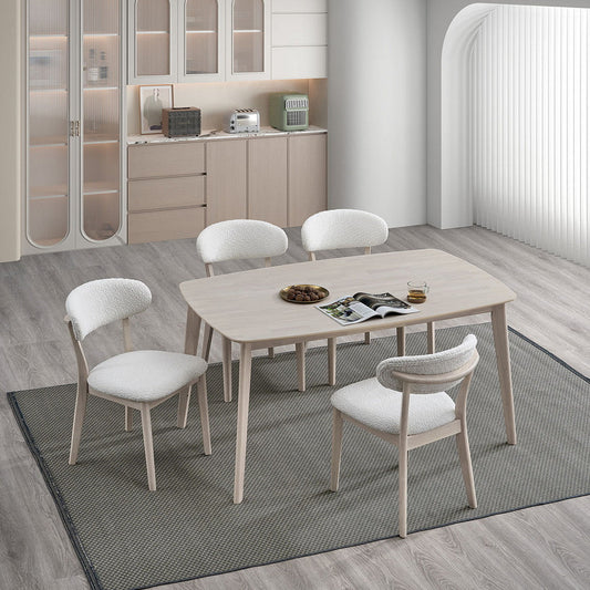 White-washed Scandinavian dining table with curved upholstered chairs in a bright breakfast area