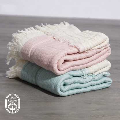 Pink reversible cotton muslin baby blanket in a nursery crib