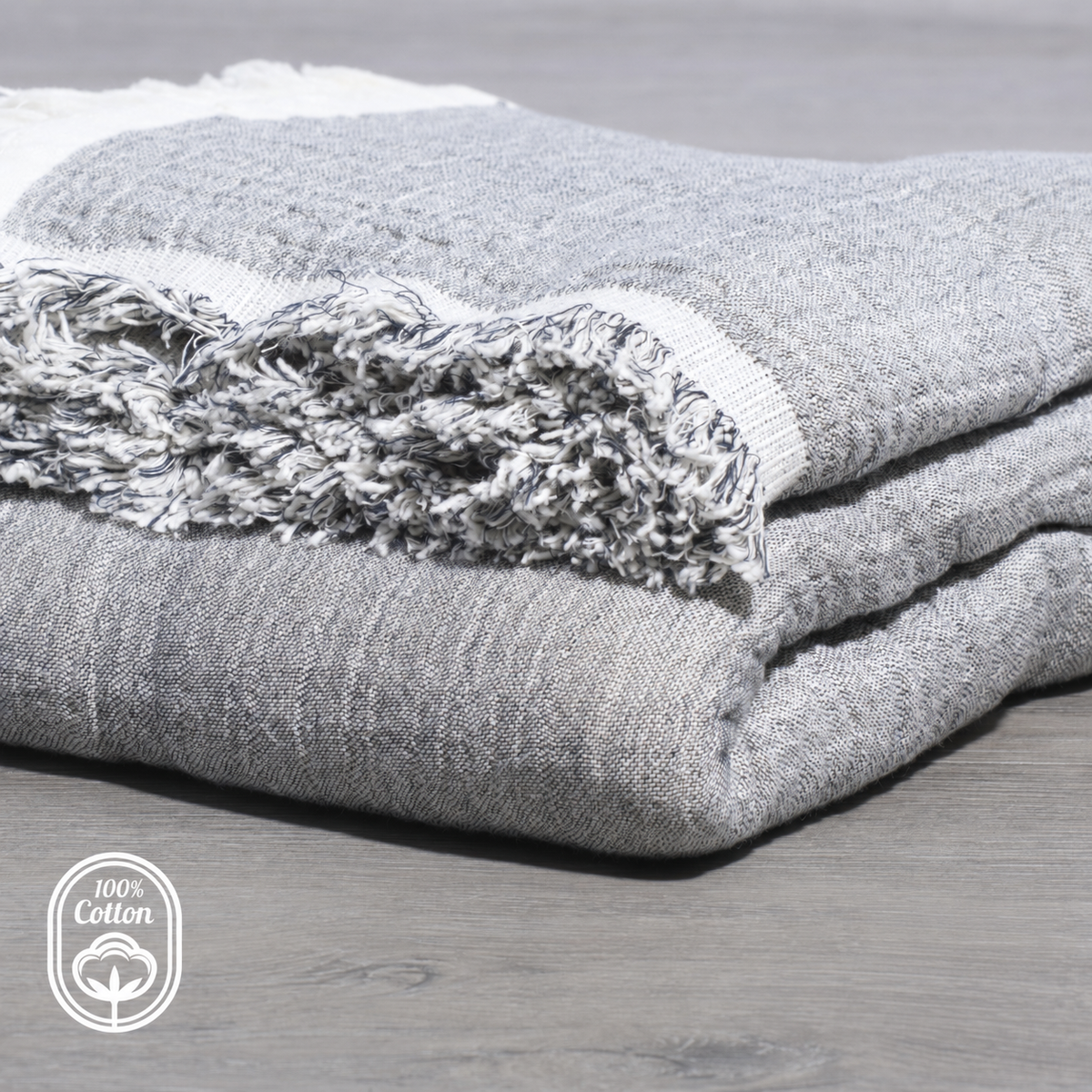 Grey and ivory reversible cotton muslin throw blanket folded on a bed