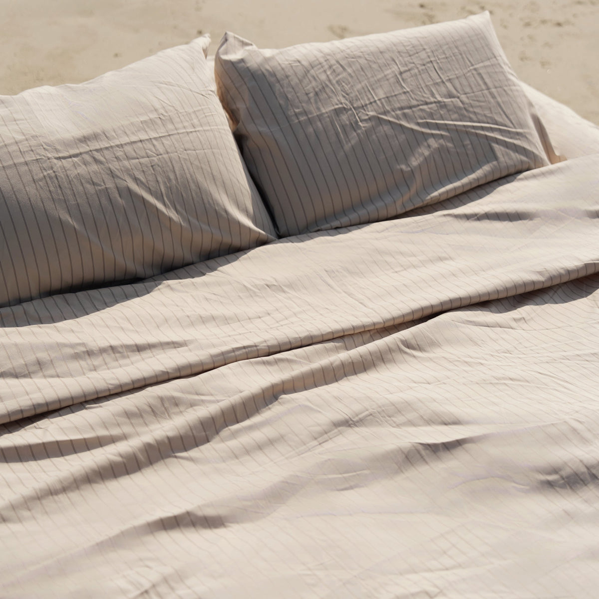 Ecru and sage Australian cotton sateen sheet set with subtle sheen on a bed in a refined bedroom