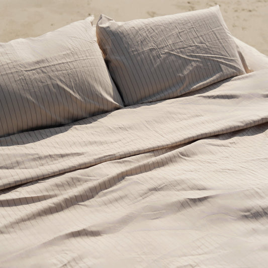 Ecru and sage Australian cotton sateen sheet set with subtle sheen on a bed in a refined bedroom