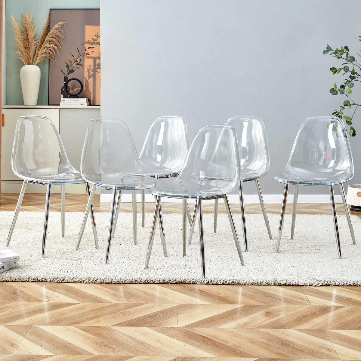 Six clear transparent PET dining chairs with silver metal legs around a modern dining table