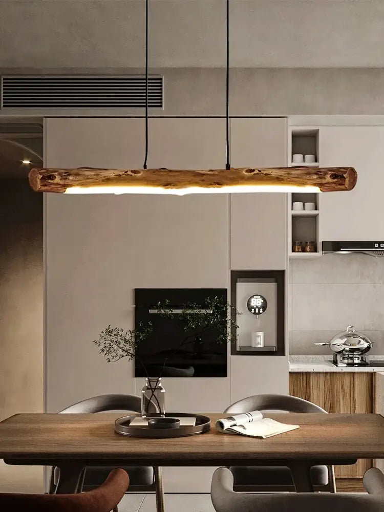 Minimalist black walnut linear pendant light hanging over a kitchen island in a modern kitchen