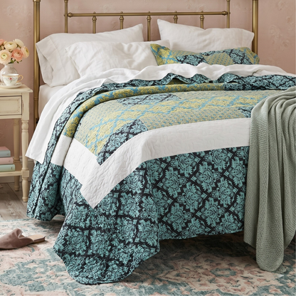 Turquoise damask baroque scalloped quilt set with shams on a bed in a bright bedroom