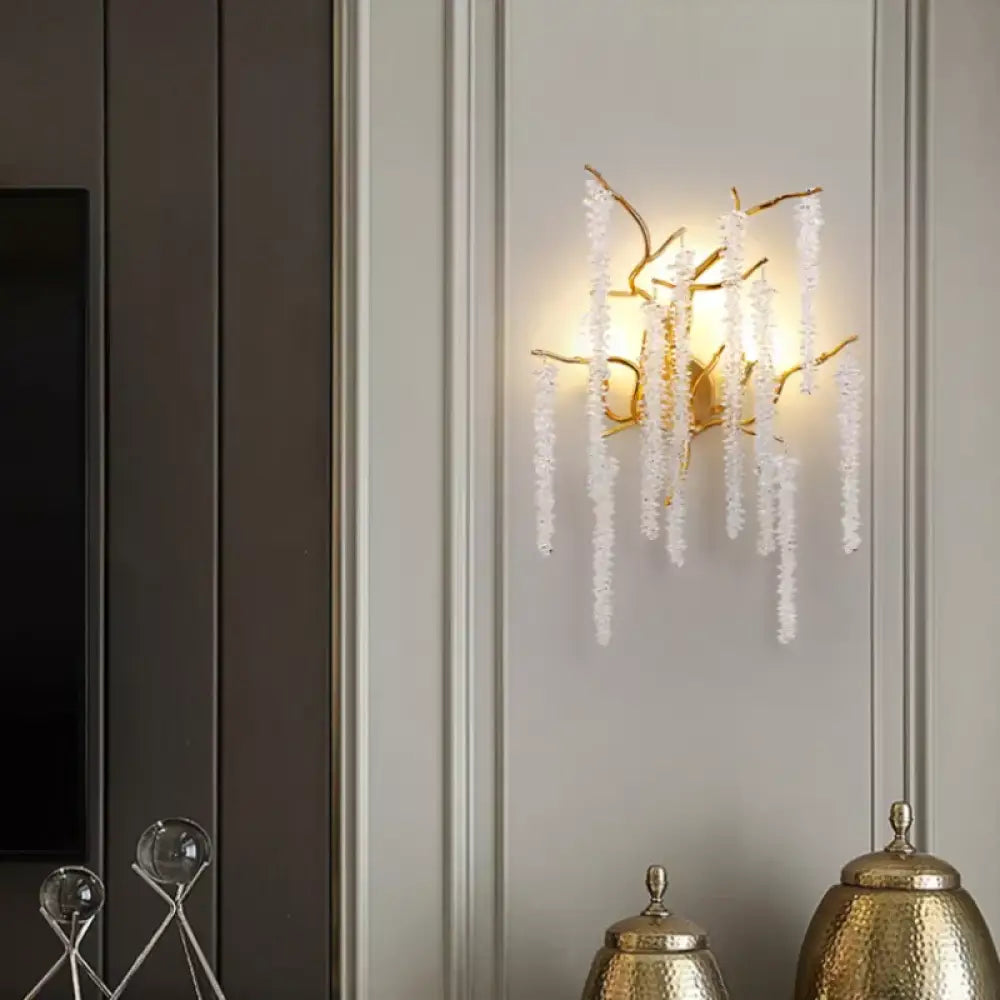 Gold crystal cherry blossom wall sconce with branching frame lighting a modern bedroom wall
