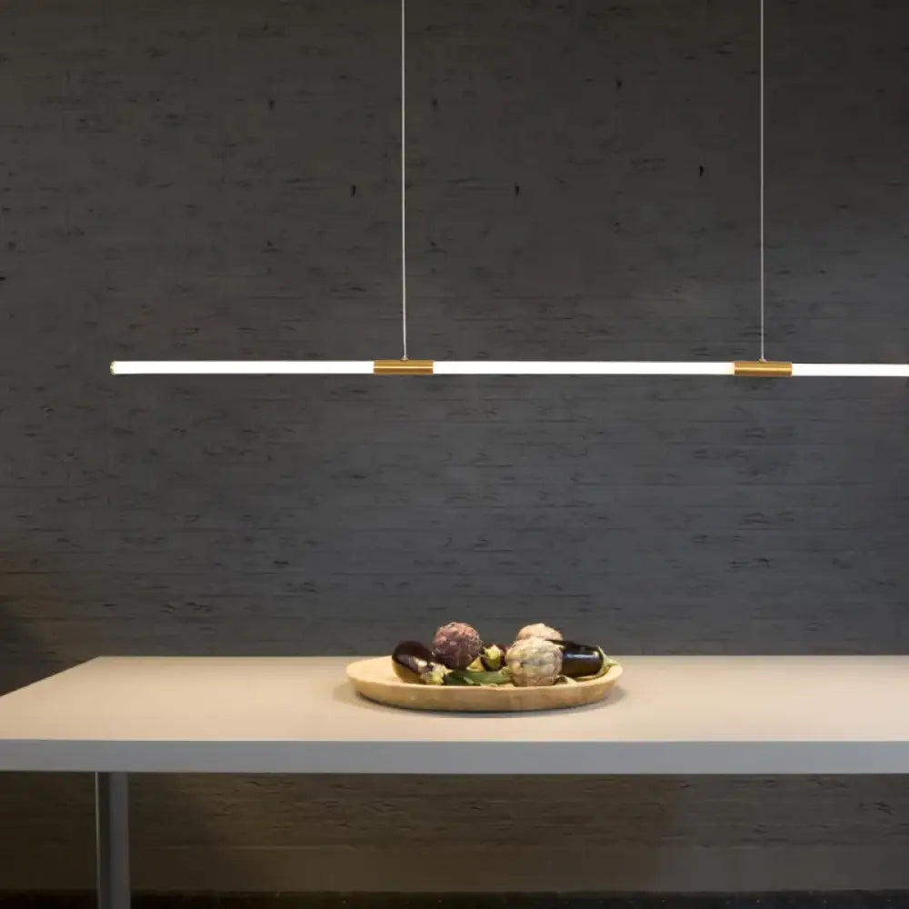 Copper-plated linear LED pendant light with acrylic light pipe hanging over a home office desk