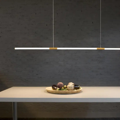 Copper-plated linear LED pendant light with acrylic light pipe hanging over a home office desk