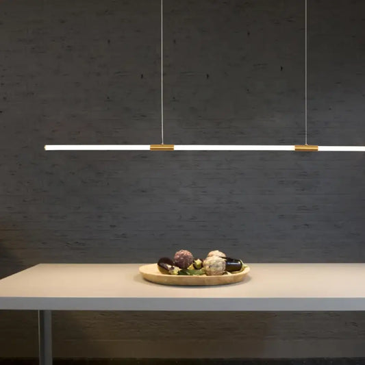 Copper-plated linear LED pendant light with acrylic light pipe hanging over a home office desk