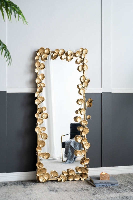 Full-length floor mirror with gold leaf iron frame leaning against a bedroom wall