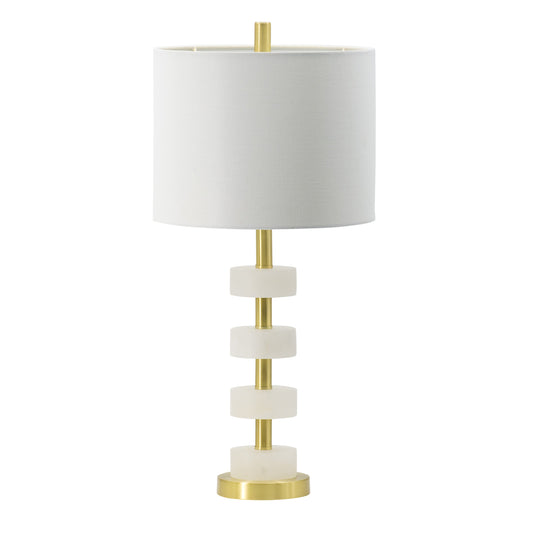 White marble table lamp with gold brass frame and white drum shade on a bedroom nightstand