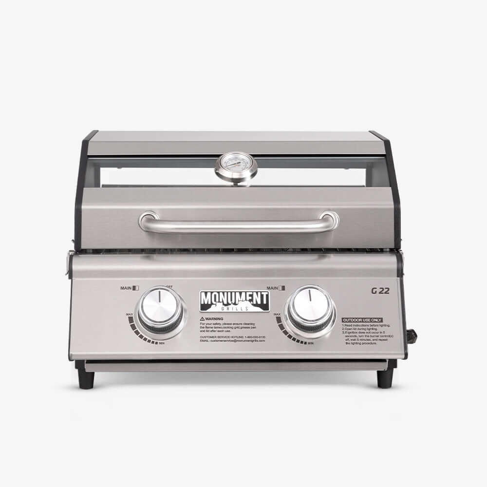 G22 stainless steel portable tabletop propane gas grill with locking lid at a campsite