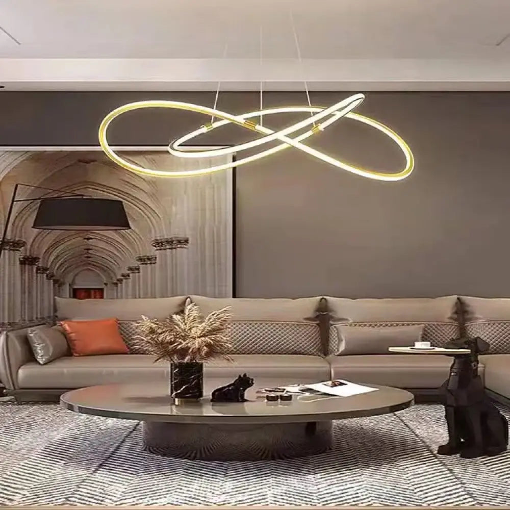 Modern gold dimmable LED pendant light hanging in a bright contemporary living room