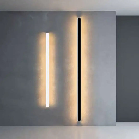 Black modern LED linear wall sconce lighting a dining room wall with a long strip of light