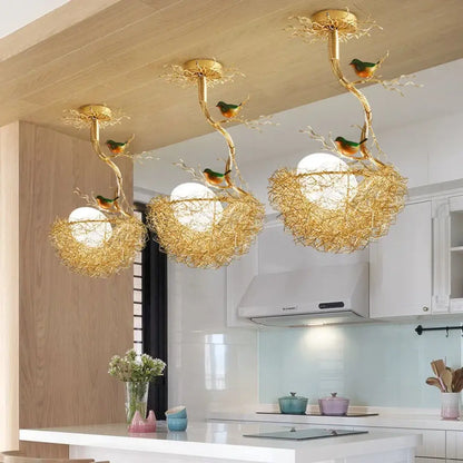 Modern gold bird's nest LED ceiling light with glass ball pendants over a kitchen island