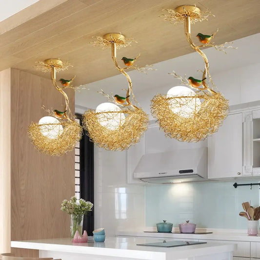 Modern gold bird's nest LED ceiling light with glass ball pendants over a kitchen island