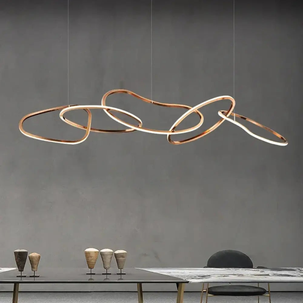 Gold modern LED multi-ring pendant light glowing above a dining table in a contemporary room