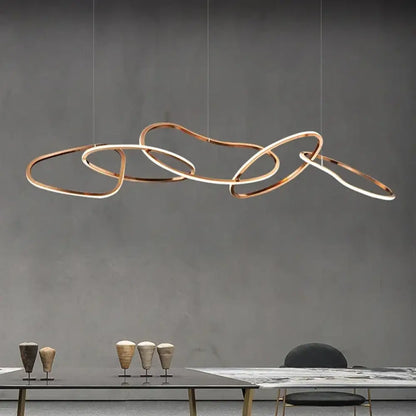 Gold modern LED multi-ring pendant light glowing above a dining table in a contemporary room