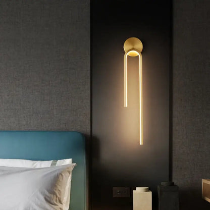 Gold LED modern signature wall sconces mounted in a pair on each side of a bed