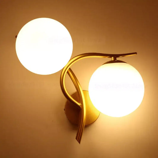 Black Nordic iron wall sconce with glass ball shade beside a bed in a modern bedroom
