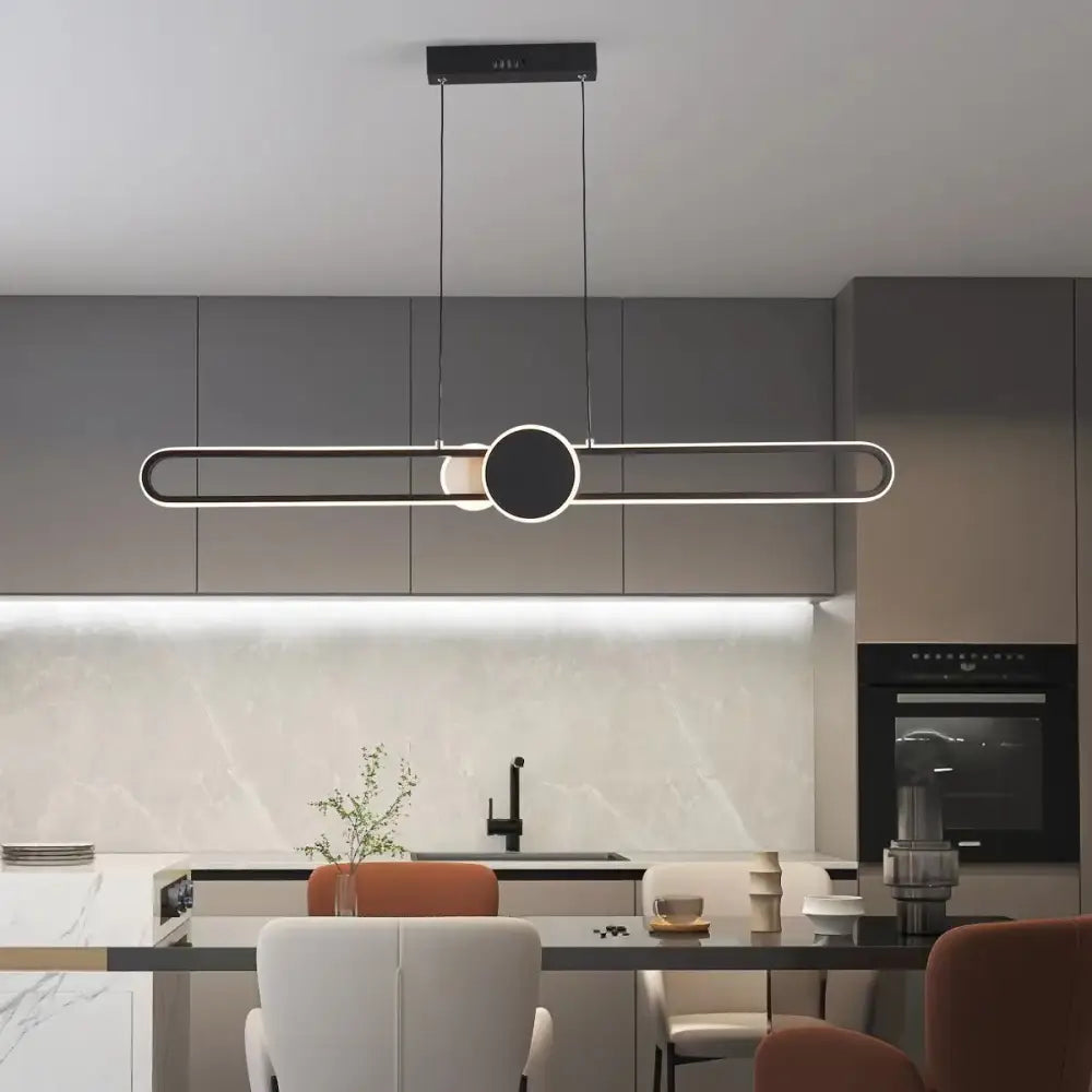 Minimalist black LED strip pendant light hanging above a kitchen island with remote dimming