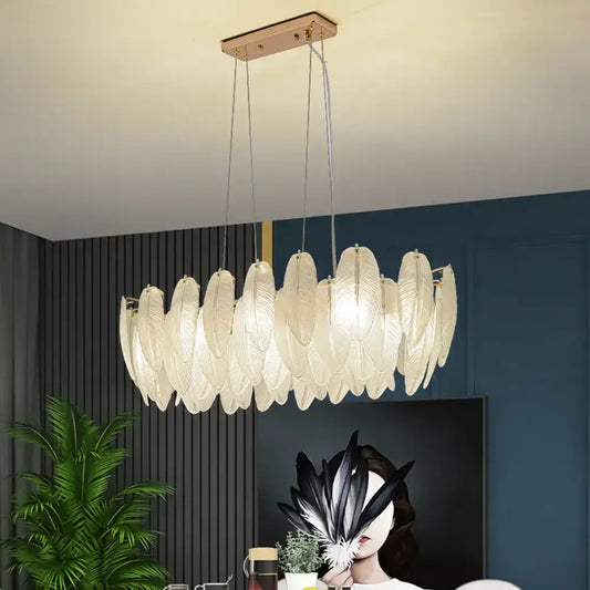 Gold feather design LED chandelier glowing above a kitchen island in a modern home