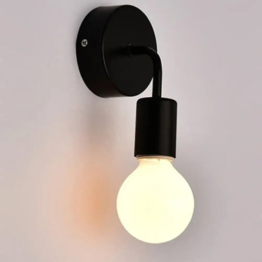 Modern black wall sconce mounted on a hallway wall beside a staircase