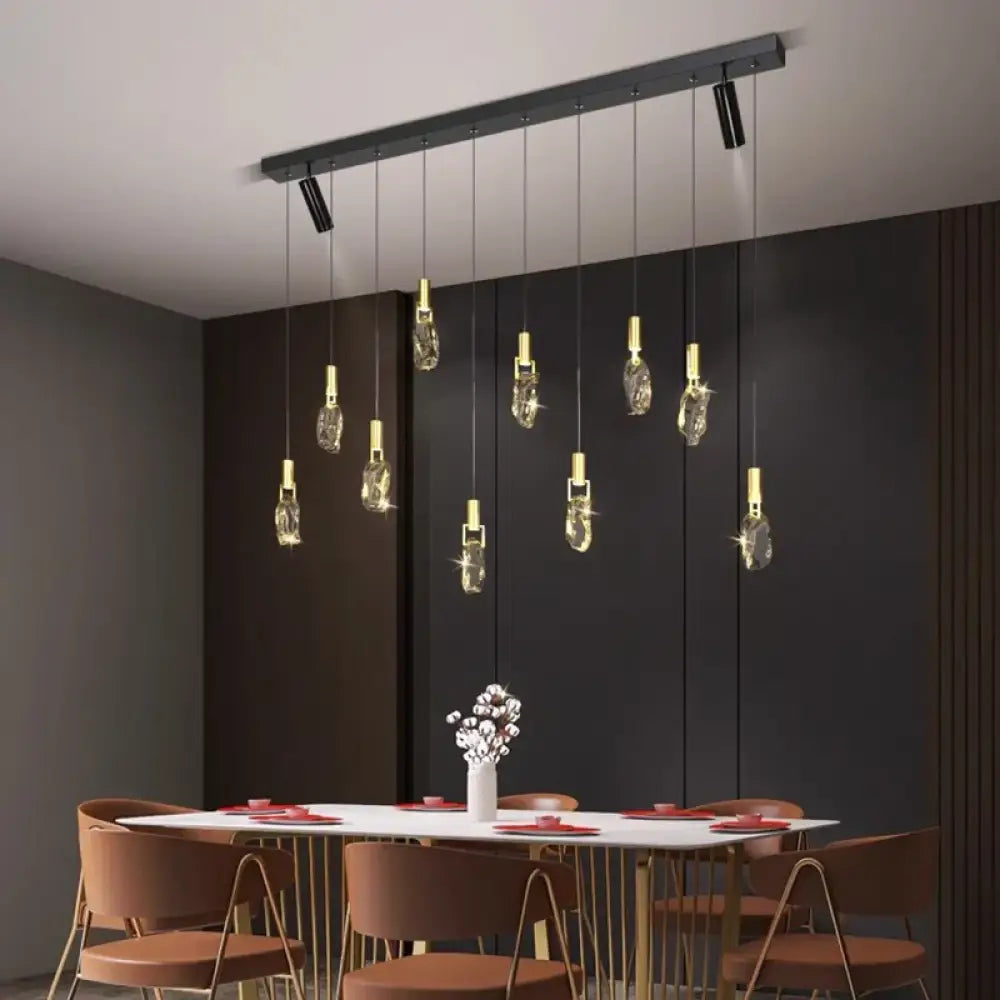 Modern linear multi-head pendant light hanging over a long dining table in a contemporary home