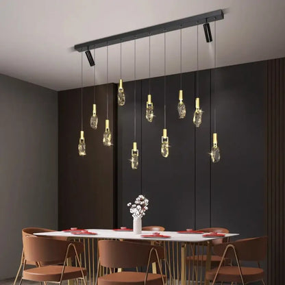 Modern linear multi-head pendant light hanging over a long dining table in a contemporary home