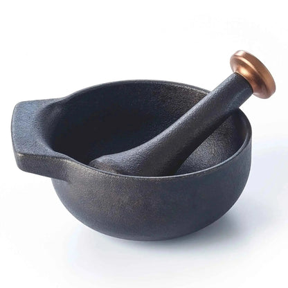 Enameled cast iron mortar and pestle with fresh herbs and spices on a kitchen counter