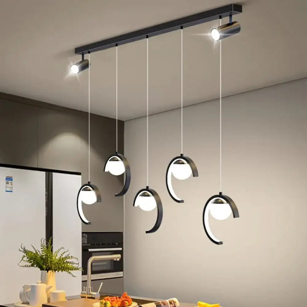 Sleek gold modern chandelier with five heads hanging above a dining table in a bright room