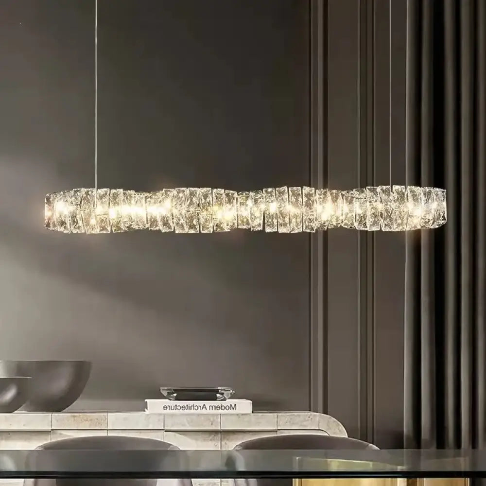 Chrome K9 crystal ring LED chandelier glowing above a modern dining room table