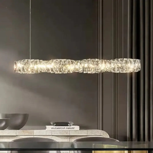 Chrome K9 crystal ring LED chandelier glowing above a modern dining room table
