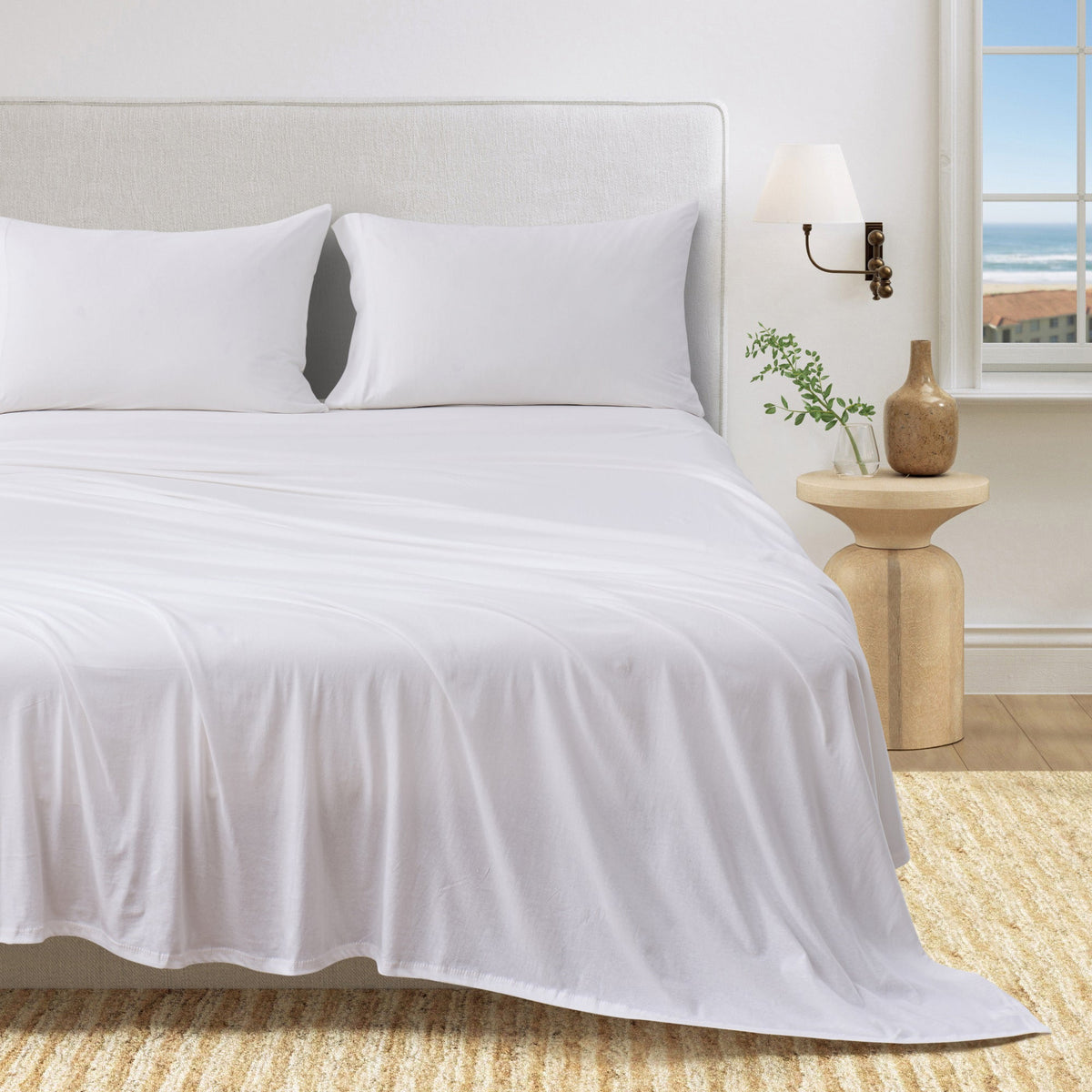 Fog grey organic cotton jersey knit sheets on a neatly made bed in a calm bedroom