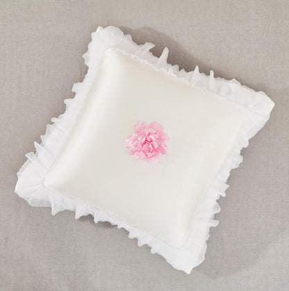 Pearl white satin euro sham with pleated ruffles and pink rose accents on a romantic bed