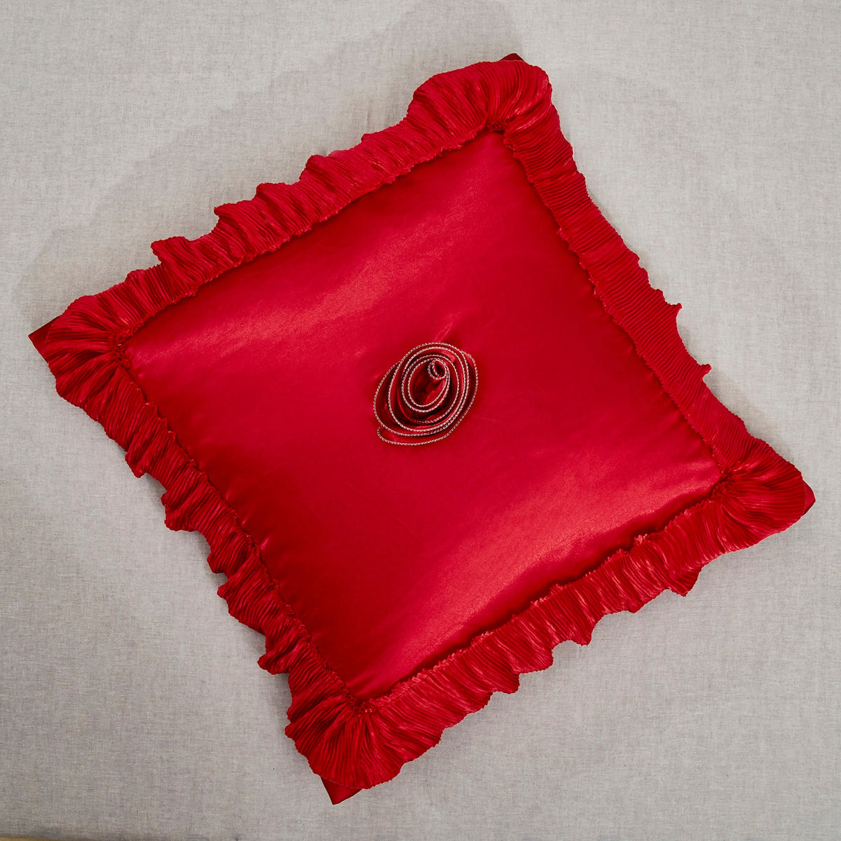 Bright red satin ruffle euro sham with floral embellishments on a glamorous bed