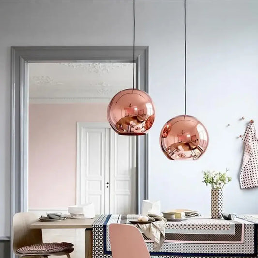 Vintage copper glass ball pendant light hanging beside a bed in a cozy loft-style bedroom