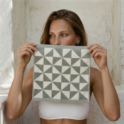 Sage and ecru Umbra Australian cotton towels with triangular print hanging in a bright bathroom