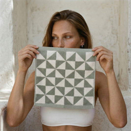Sage and ecru Umbra Australian cotton towels with triangular print hanging in a bright bathroom