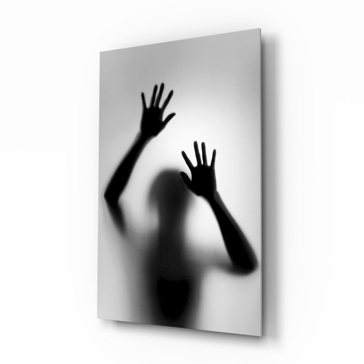 Black and white silhouette of hands pressed against frosted glass wall art in a hallway